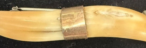 Close-up of engraved gold-tone collar joining the two boar tusks on Victorian brooch pin