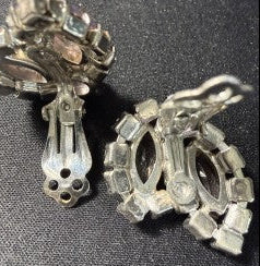 Back view of vintage silver-tone rhinestone clip-on earrings showing open oval frame design