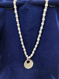 Full view of jade and freshwater pearl necklace with mother of pearl pendant on blue velvet