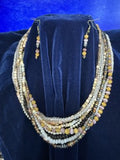 Multistrand beaded necklace and coordinating earrings displayed on a dark blue velvet jewelry bust