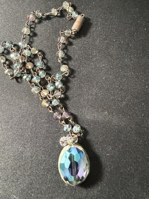 Close-up of iridescent blue-green oval pendant and AB crystal beads