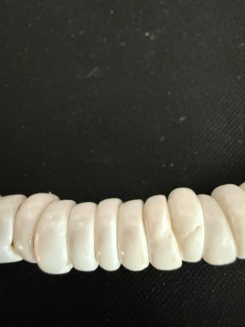 Close-up detail of uniform white puka disc shell beads