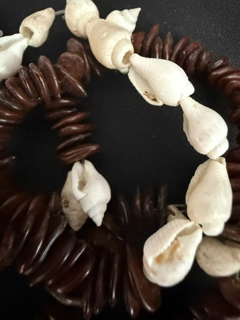 Close-up of cowrie and spiral shell accents on kukui seed strand