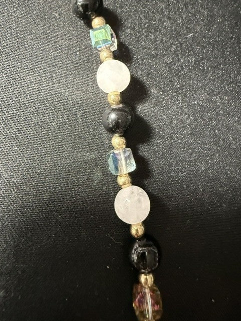 Close-up of white onyx coin beads, black onyx rounds, and peacock glass cube beads