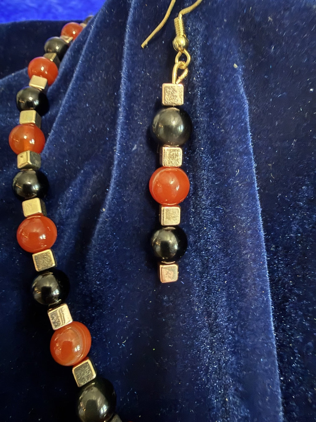 Close view of the orange jasper and black stone beads, gold-tone spacers, and matching earrings