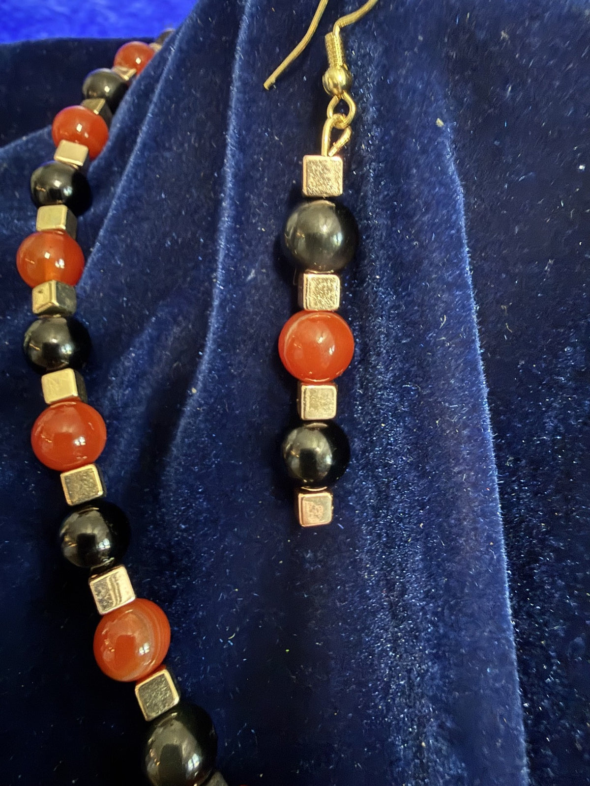 Close view of the orange jasper and black stone beads, gold-tone spacers, and matching earrings