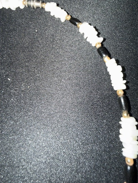 Close-up of white shell chips alternating with black tube beads and gold spacers