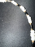 Close-up of white shell chips alternating with black tube beads and gold spacers