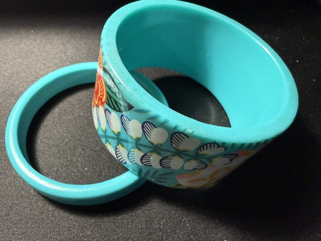 Two teal acrylic bangles stacked together showing floral print detail