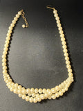 Vintage double-strand faux pearl necklace laid flat on dark fabric