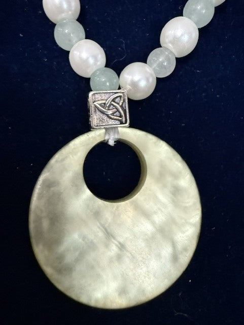Close-up of Celtic knot connector and mother of pearl donut pendant with jade and pearl beads