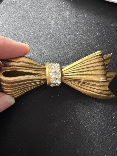 Vintage gold-tone bow brooch with rhinestones - held in hand for scale