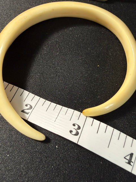 Antique wild boar tusk carved bracelet, side view showing near-complete circle with ruler for scale