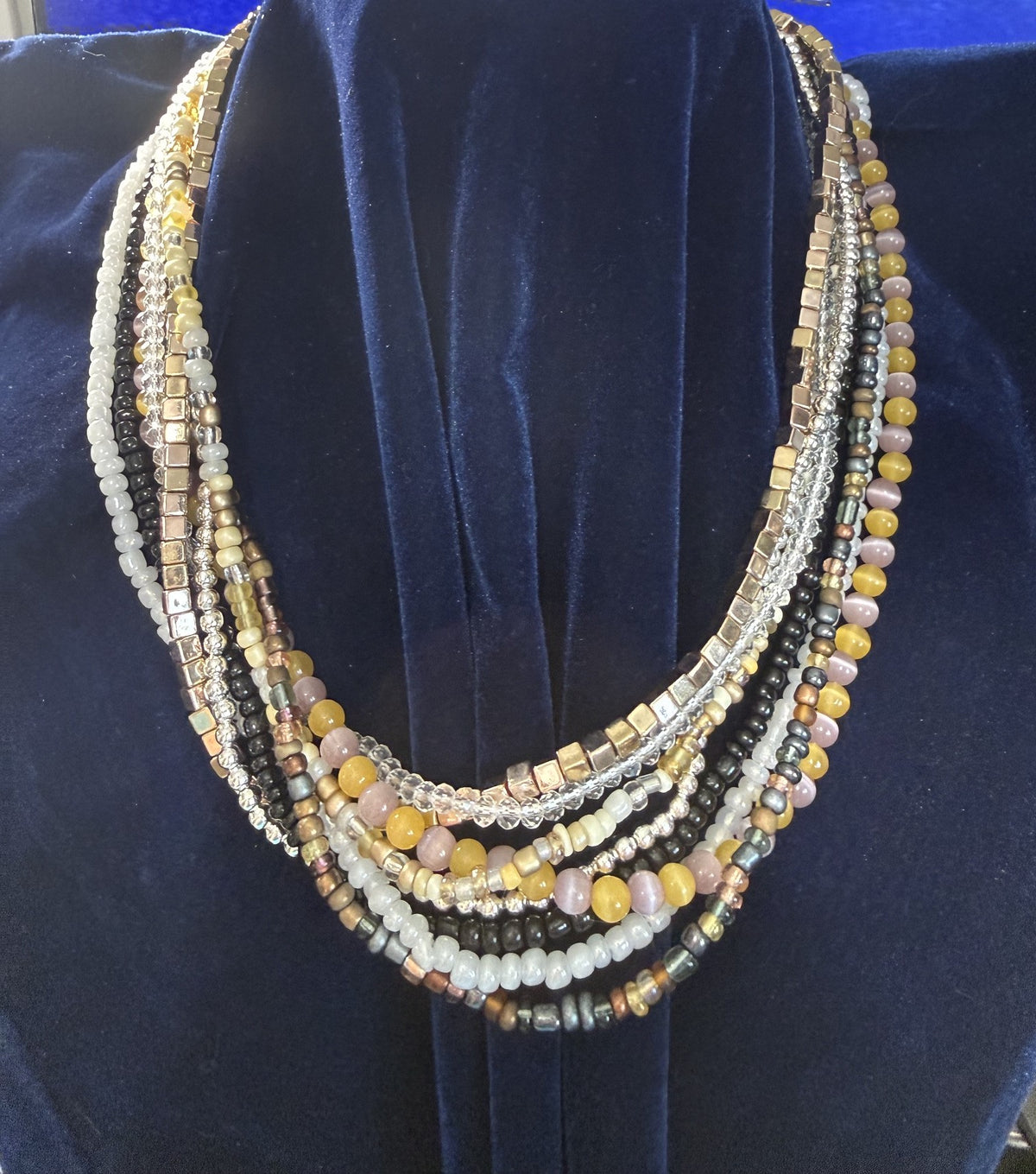 Close view of the layered black, white, silver-tone, gold-tone, blush-pink, and golden-yellow beadwork