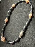Natural hematite and pink cat's eye gemstone bracelet showing full length with ornate silver focal bead and gold accent spacers