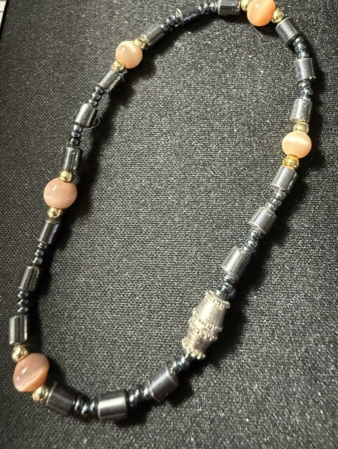 Natural hematite and pink cat's eye gemstone bracelet showing full length with ornate silver focal bead and gold accent spacers