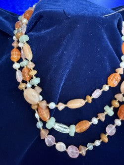 Close-up of 3-strand gemstone necklace drape on navy velvet