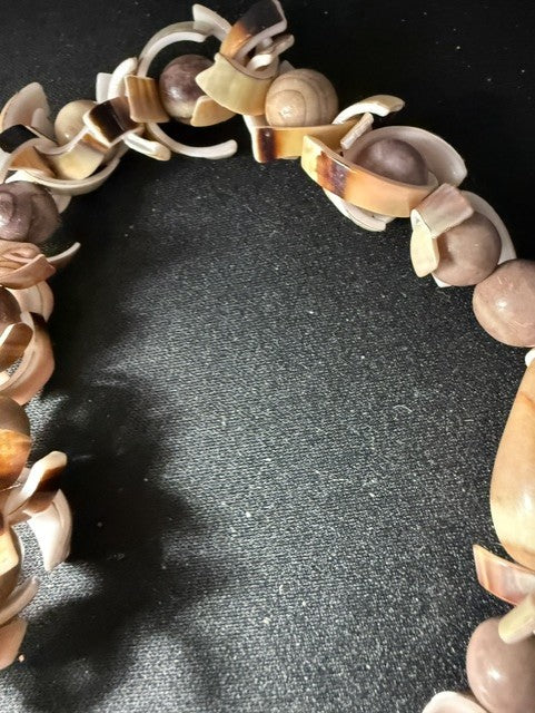 Detail showing spiral snail shells and spotted oval beads