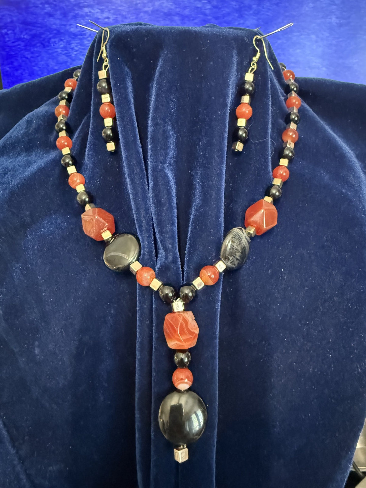 One-of-a-kind jasper, onyx, and black jasper necklace and matching earrings displayed on blue velvet