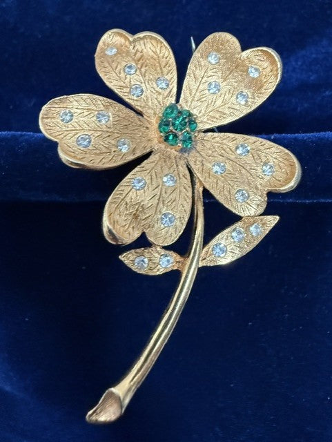 Vintage JJ gold-tone flower brooch front view showing emerald green and clear rhinestones