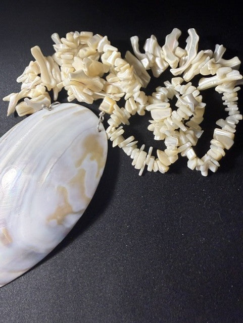 Natural iridescent shell pendant showing cream and tan swirling pattern, with coral strand