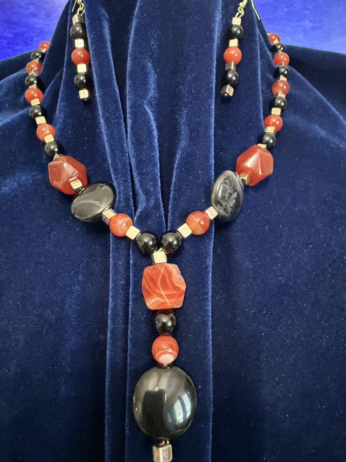 Pendant detail showing the orange jasper focal bead and glossy black drop on a handmade necklace