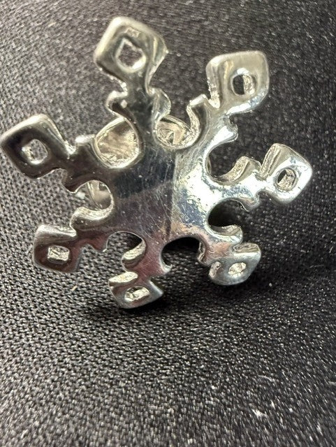 Vintage sterling silver snowflake pin flat lay on dark fabric