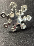 Vintage sterling silver snowflake pin flat lay on dark fabric