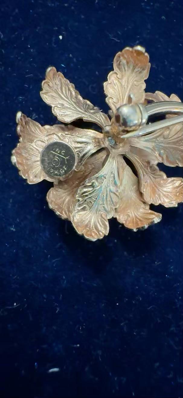 Vintage gold-tone flower brooch back showing maker's mark